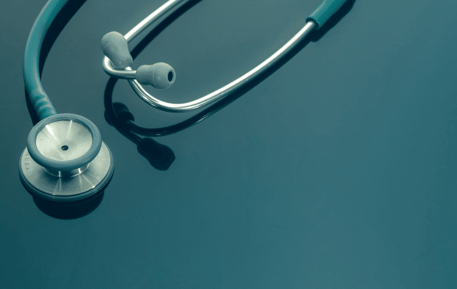 Stethoscope on a reflective blue surface, suggesting medical theme.
